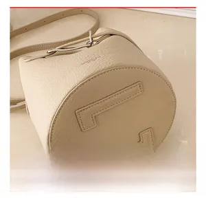 Detailed macro view of the neat H-pattern stitching on the beige leather bucket bag base