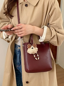 Sac seau bordeaux minimaliste avec charme d'ours en peluche et trench-coat élégant