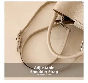 Detail of adjustable shoulder strap and leather texture on a beige bucket bag