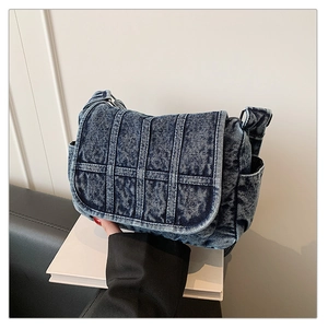 Detail showing high-quality dark blue denim fabric texture and stitching on the flap bag