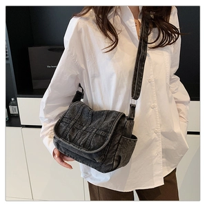 Close-up of vintage black denim crossbody bag featuring vertical stitching and side pockets