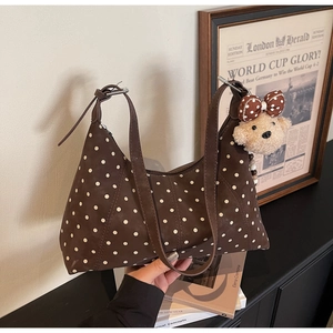 Close-up of brown polka dot shoulder bag featuring a cute plush bear charm accessory