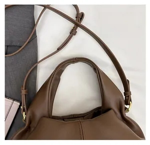 Close-up of brown leather bag showing lychee grain texture and gold hardware details