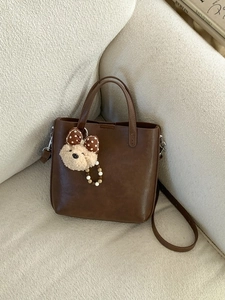 Sac seau marron élégant avec bandoulière amovible et breloque ours pour un usage quotidien