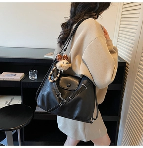 Detail of black soft leather multi-functional shoulder bag with metal eyelets and plush charm