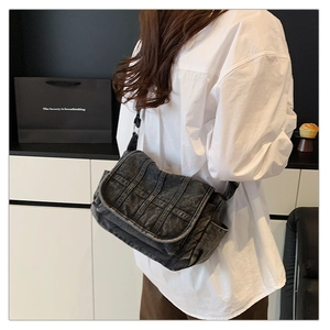 Detail of grey washed denim crossbody bag featuring vertical quilted stitching and pockets