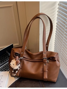Brown litchi grain leather tote bag with bear charm in a stylish office setting