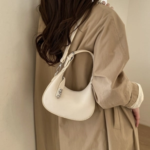 Détail du sac croissant beige minimaliste avec texture litchi et fermoir en métal argenté
