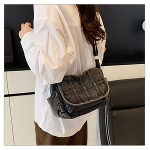 Detail of vintage washed denim crossbody bag featuring multi-pocket design and adjustable strap
