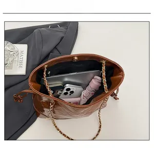 Vue intérieure du grand sac matelassé marron avec chaîne, contenant tablette et mobile