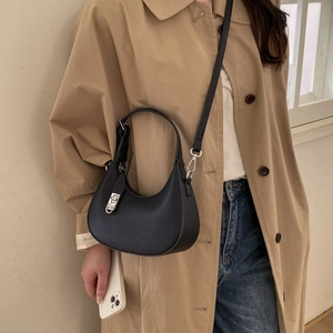 Détail du sac demi-lune en cuir noir avec un fermoir rotatif en métal argenté brillant
