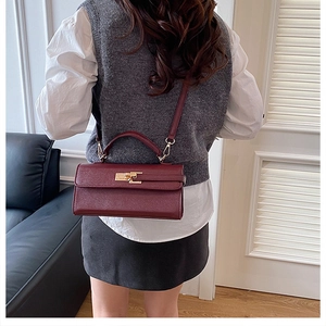 Detail view of burgundy handbag with litchi grain texture and gold twist lock closure