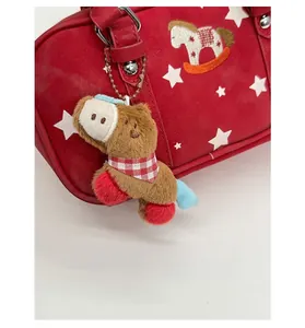 Close-up of a brown plush horse charm with red scarf on a stylish handbag detail