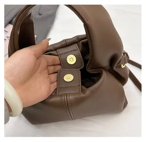 Close-up of dual golden magnetic buckle closure on a brown pebble leather cloud bag