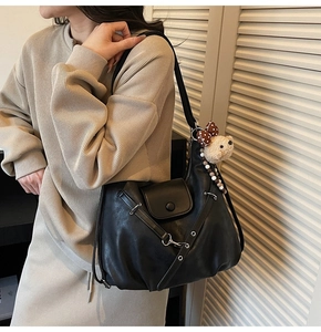 Detail of black retro hobo bag with silver hardware and cute plush bear charm