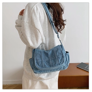 Detail showing the denim fabric texture and stitching of the crossbody shoulder bag