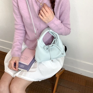 Detail view of light blue leather dumpling bag featuring a delicate bow and silver beads