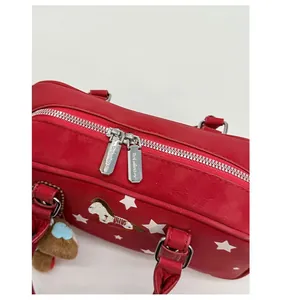 Detail of red pillow bag featuring white star prints and dual silver metal zippers