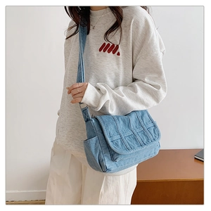 Detail of light blue denim crossbody bag with woven texture and adjustable strap