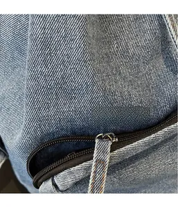Detailed macro view of light blue denim fabric with black zipper and orange stitching