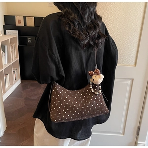Brown polka dot hobo bag with cute bear charm shown on model in a cozy indoor setting