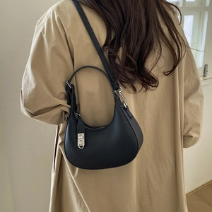 Détail d'un sac hobo en cuir grainé noir porté à l'épaule sur un mannequin élégant