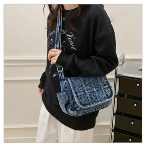 Macro detail of vintage washed denim crossbody bag featuring woven texture and adjustable strap