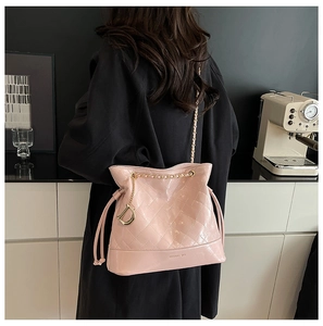 Détail du sac seau matelassé rose avec bandoulière chaîne dorée et pendentif en D