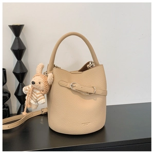 Detail of beige bucket bag in lychee leather featuring a cute bunny plush charm