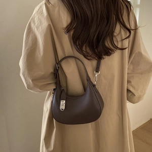 Gros plan du sac hobo marron foncé avec fermoir rotatif argenté sur cuir grainé