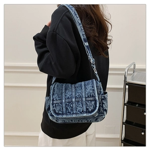 Model view of a vintage blue denim crossbody bag with snowflake texture and flap cover