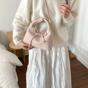 Detailed close-up of pink leather handbag featuring bow strap and silver ball metal charms