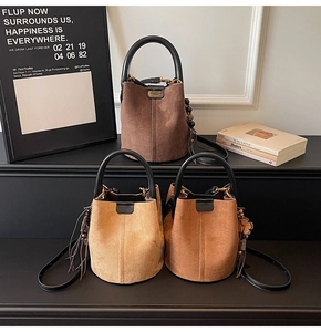 Detailed view of suede bucket bags with drawstring closure and leather tassel charms