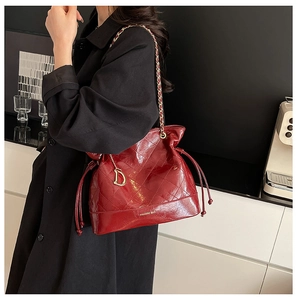 Détail du sac seau bordeaux matelassé avec bandoulière chaîne et pendentif en métal D