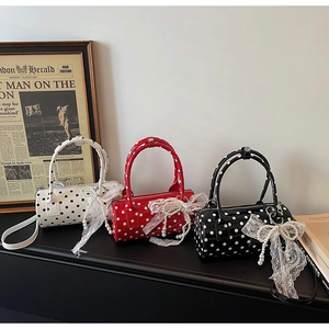 Close-up of cylinders bags in polka dot faux leather with lace bows and pearl charms