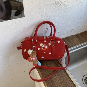 Detailed view of red Boston bag with star patterns, horse embroidery and plush charm