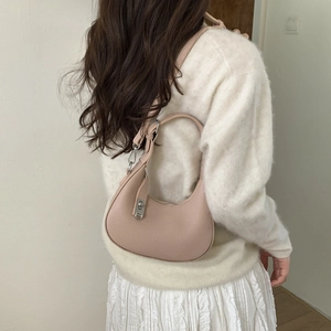 Détail d'un sac hobo en cuir rose porté par un mannequin dans un décor intérieur minimaliste