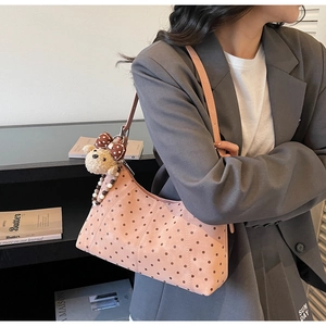 Detailed close-up of pink polka dot shoulder bag with cute plush bear and bead charms