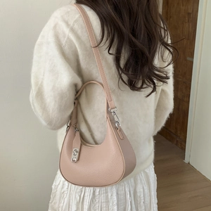 Détail du sac demi-lune rose nude en cuir grainé avec fermoir rotatif en métal argenté