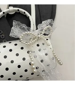 Detailed macro view of white polka dot handbag with lace bow and pearl charm accents