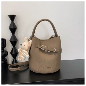 Detail of coffee brown bucket bag with lychee texture and beige knit animal charm