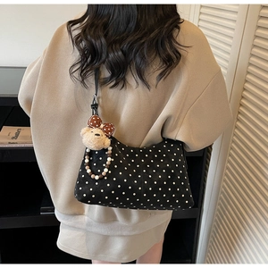 Detail of black polka dot shoulder bag with cute plush bear charm and beaded chain