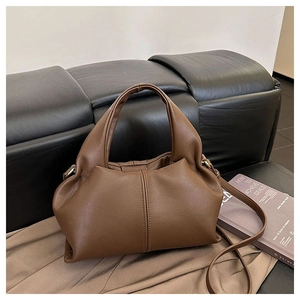 Detail of soft brown leather texture and elegant pleated design on a chic crossbody bag