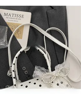 Close-up of white polka dot barrel bag with lace and pearl bow decoration