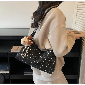 Detail of black polka dot shoulder bag featuring cute bear charm and beaded accessories