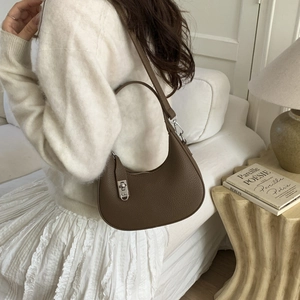 Gros plan d'un sac hobo en cuir grainé marron foncé avec une boucle métallique argentée