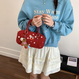 Detail of red pillow bag featuring white stars, pony embroidery, and plush charm accessory
