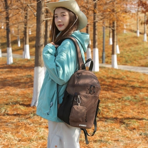 Detail of brown plaid nylon backpack with side mesh pockets and mini hanging pouch in forest