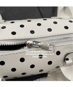 Close-up of polished metal zipper slider on a white polka dot cylindrical handbag