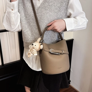Close-up of brown litchi pattern leather bucket bag with a cute knit rabbit charm